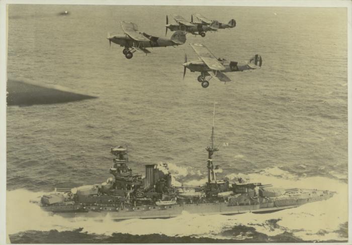 British battleship "HMS BARHAM" (1914) escorted by aircraft as it enters a harbour