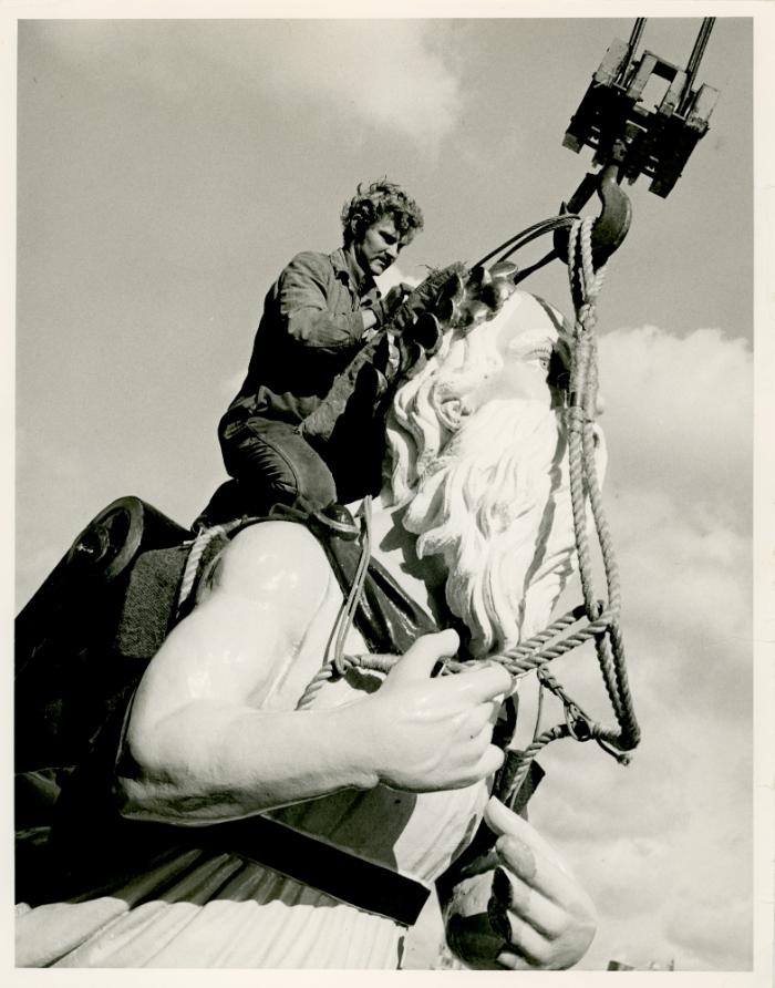 A man fastening a ship's figurehead or 'pulena' for transportation