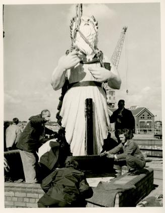 A group of men preparing a ship's figurehead or 'pulena' for transportation