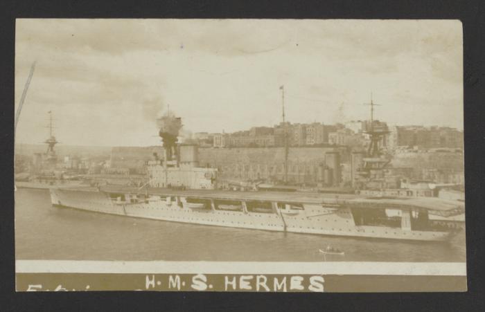 British aircraft carrier HMS Hermes (95) in the foreground; unidentified large surface warship and Admiralty Floating Dock No. 8 beneath Corradino heights in the background