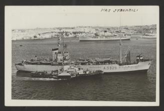 Italian Vesuvio-class auxiliary ship Stromboli (A5329) alongside a harbour tug and with a vessel in the background