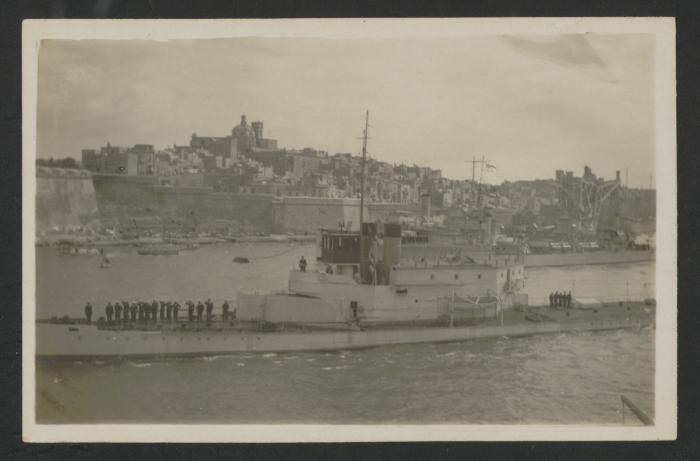 Surface warship in Grand Harbour, Malta, with Senglea, another surface vessel and a floating crane in the background