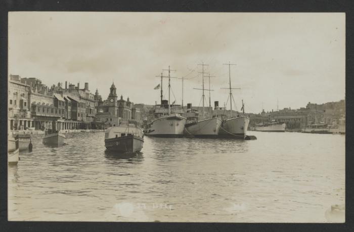 Row of surface vessels and other craft in Dockyard Creek, with the Royal Naval Bakery in the background