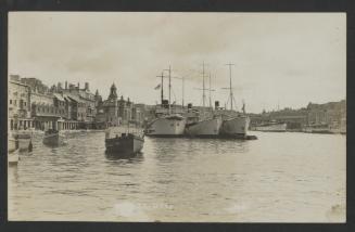 Row of surface vessels and other craft in Dockyard Creek, with the Royal Naval Bakery in the background